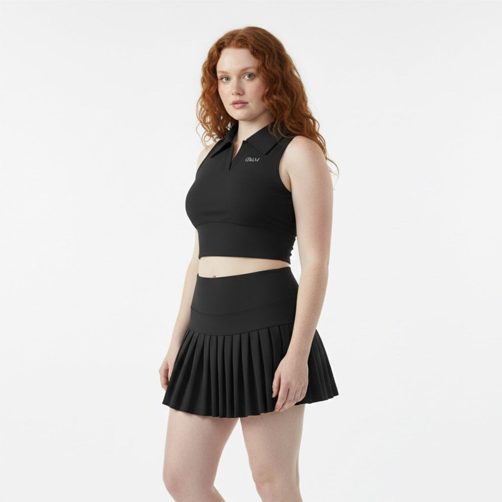 Woman wearing a black sleeveless top and skirt with white sneakers on a white background